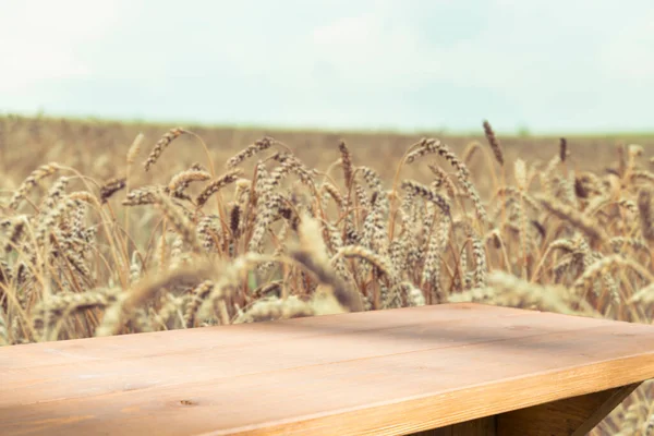 Table en bois devant le champ de blé au coucher du soleil. Montages prêts pour l'affichage des produits — Photo