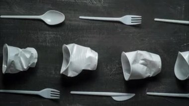 plastic problem concept, stop motion animation, place for text, white plastic dishes move on black background