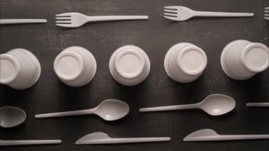 plastic problem concept, stop motion animation, place for text, white plastic dishes move on black background