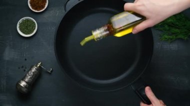 Man pouring cooking oil on the frying pan - Top View on a dark background