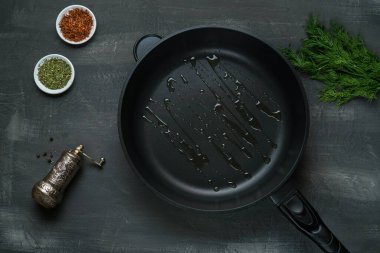 Man pouring cooking oil on the frying pan - Top View on a dark background