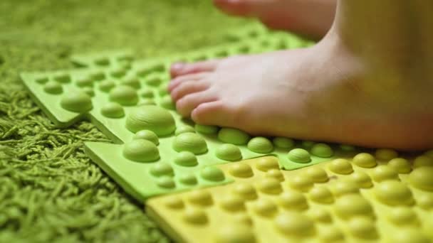 Massagem nos pés, a criança pisa sobre um tapete de massagem descalço, close-up — Vídeo de Stock
