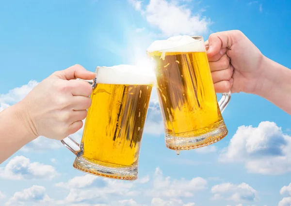 Звон бокалов пива на фоне неба — стоковое фото