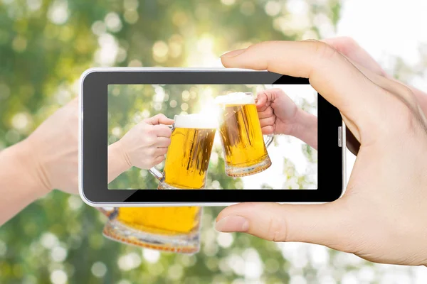 На телефоне стаканы "Звон пива" на размытом фоне . — стоковое фото