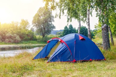 Arka plan ağaç üzerinde Nehri yakınında kampında çadır.