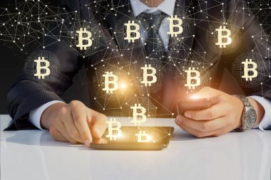Bitcoin ile telefon ve tablet üzerinde çalışan iş adamı.