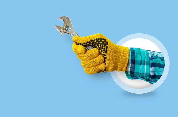 Hand with a wrench on a blue background.