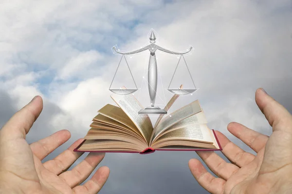 Hands of the lawyer show the scales and the book of justice.