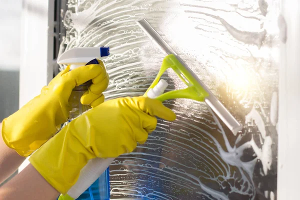 Limpiador con un raspador y spray lava una ventana  . —  Fotos de Stock