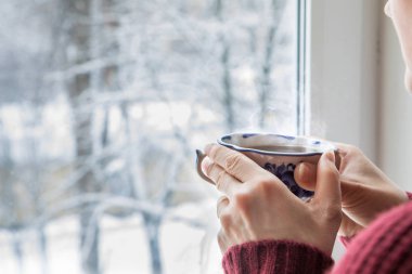 Bir fincan çay bir kazaklı pencerenin yakınındaki.