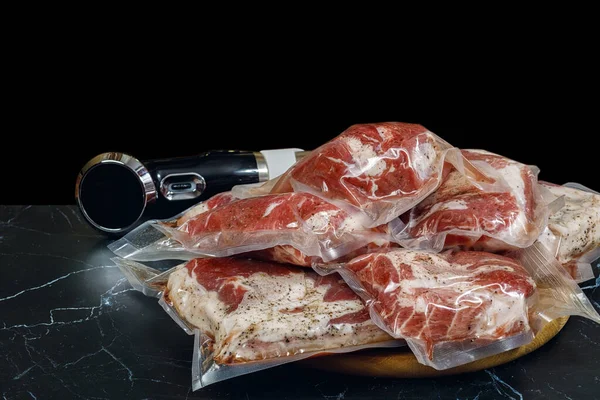 Sous vide immersion circulator cooker and the meat Packeds on a dark background . — Stock fotografie