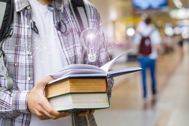 Eğitim ve geliştirme kavramı. Açık ders kitabı ve bulanık arkaplanda yanan bir ampul olan öğrenci.