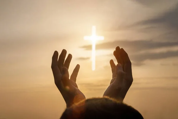 Concept of prayer and religion. Hands reach for the sky and the Cross.