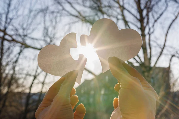 The concept of the interaction of love. Hands combine Two hearts in the form of puzzles.