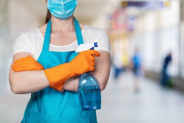 Dezenfeksiyon ve temizlik kavramı. Geçmişi bulanık, elinde sprey olan temizlikçi kadın..
