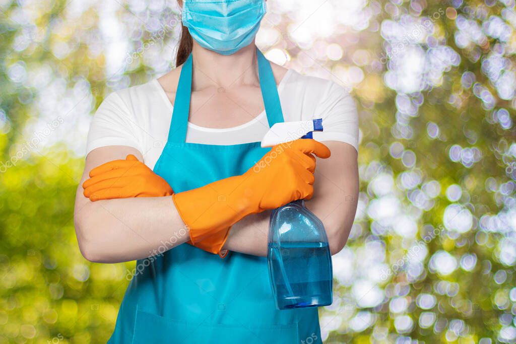 The cleaning lady stands with spray in hand on a blurred background.