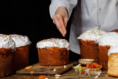 Aşçı pastaları siyah arkaplanda süslüyor..