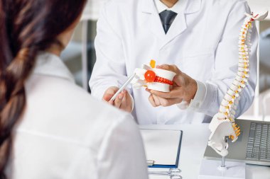 Doktor arka planda bulanık bir hastaya omurlar arası fıtık gösteriyor..