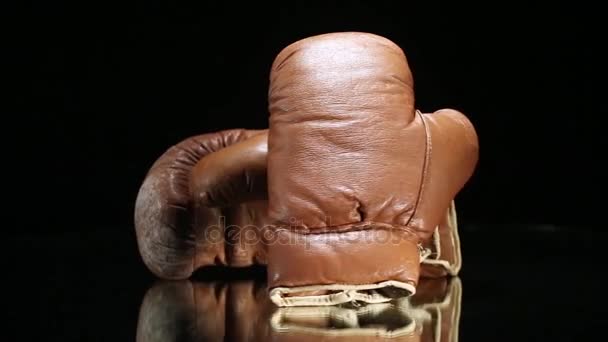 Винтажные боксерские перчатки вращаются на отражающей поверхности . — стоковое видео