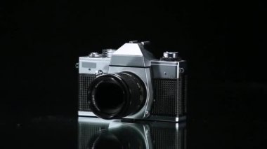 Yansıtıcı yüzeyde dönen analog fotoğraf makinesi.