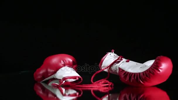 Guantes de boxeo rojos girando sobre superficie reflectante . — Vídeo de stock