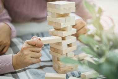 Ahşap blok bulmacaları oynayan kadın ve erkeğin eli kapalı.