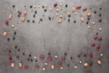 Siyah çimento zeminde tahıl, fasulye, fasulye, fasulye, fasulye, soya fasulyesi, fıstık. Üst görünüm.