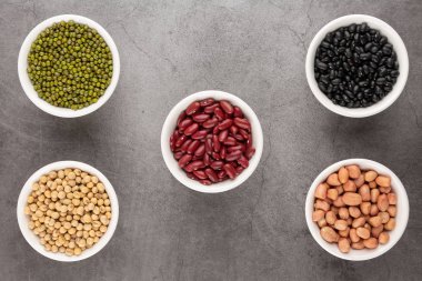 Tahıl veya fasulye, fasulye, fasulye, fasulye, fasulye, soya fasulyesi, beyaz kasede yer fıstığı, siyah çimento zemine. Üst görünüm.