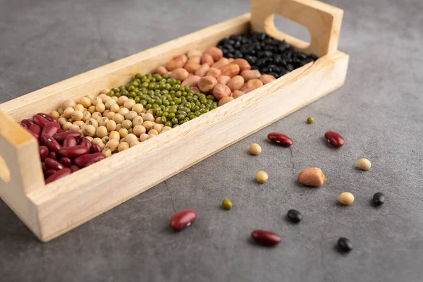 Grains or beans, red bean, black bean, green bean, soybean, peanut in the wooden tray placed on the black cement floor. High angle view.