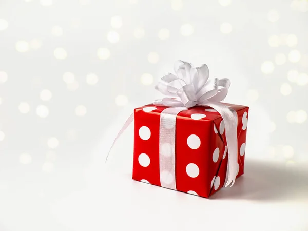 Meglepetés ajándék újév, karácsony, születésnap, barát, szeretett. Piros pöttyös doboz nagy íj fehér háttér bokeh — Stock Fotó
