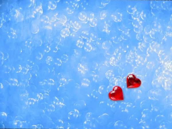 Dos corazones rojos de amantes sobre un fondo azul y borroso con bokeh . — Foto de Stock