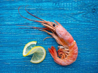 Mavi ahşap masada limonlu bir karides.