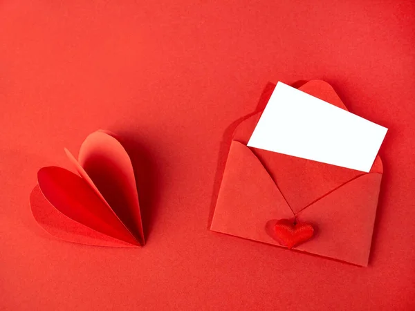 Envelope de papel vermelho com uma nota para o Dia dos Namorados em um fundo vermelho com corações . — Fotografia de Stock