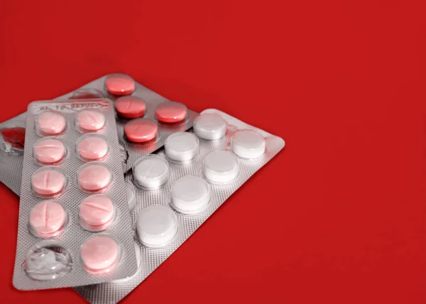 Preparação farmacêutica. Blister aberto com comprimidos sobre fundo vermelho. Medicina . — Fotografia de Stock