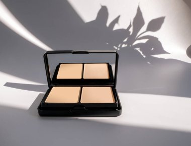 Yüze pudra. Çiçek gölgeli beyaz bir arka planda kozmetik ürünler