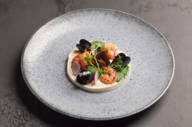 Restoran menüsü. Patates püresi ve deniz ürünleri. Turp soslu istiridye ve karides. Mavi tabak. Seramik eşyalar.