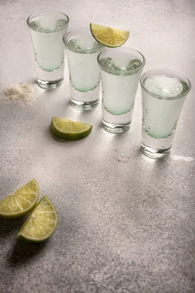 Alcohol shots. Lime with salt. Spanish and Mexican drinks. Four shots of lime. Light background
