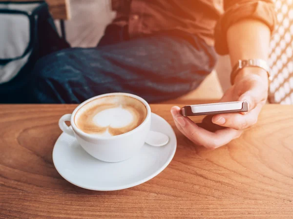 Stäng upp hand man använder telefonen i kafé med vintage filter — Stockfoto