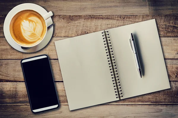 Ovanifrån notebook, penna, kaffekopp och telefon på bord av trä, Vin — Stockfoto