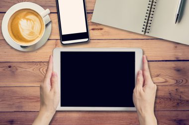 Tablet kahvehane w içinde ahşap masa üzerinde tutan el kadın
