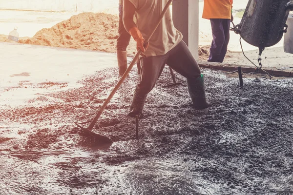 Arbeiter verteilen frisch gegossenen Betonmix auf Baustelle — Stockfoto