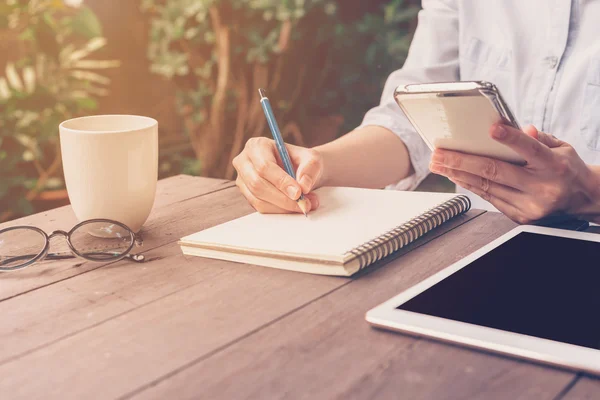 Close up hand woman writing notebook in coffee shop with vintage — Stock fotografie