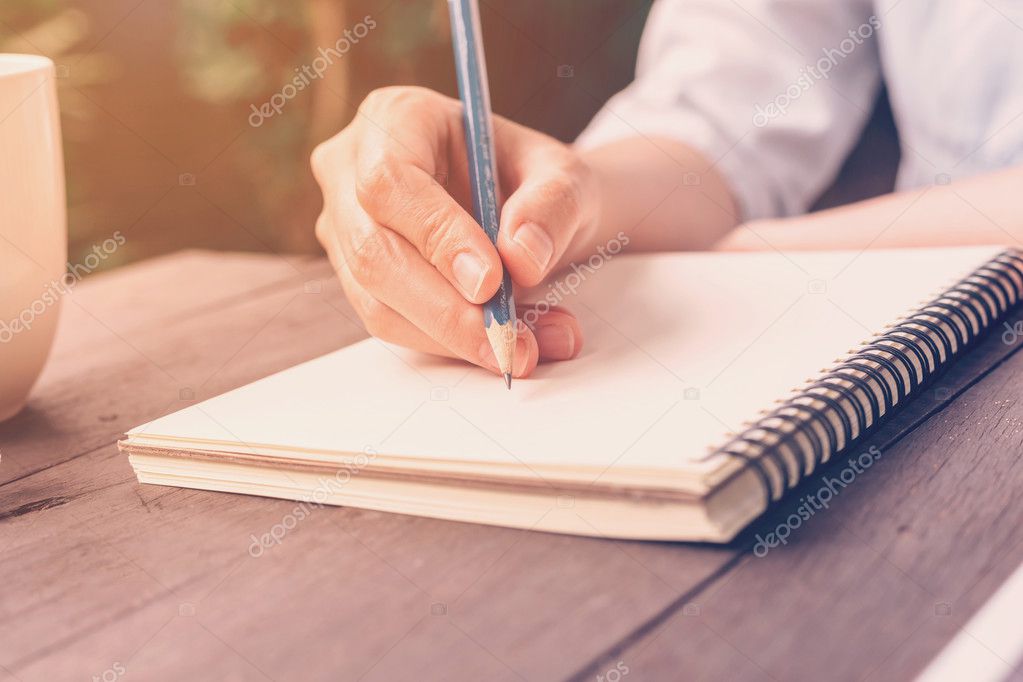 close up hand woman writing notebook in coffee shop with vintage