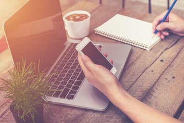 telefon tutarak ve dizüstü bilgisayar kullanan genç iş adamı el 