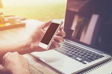 telefon tutarak ve dizüstü bilgisayar kullanan genç iş adamı el 