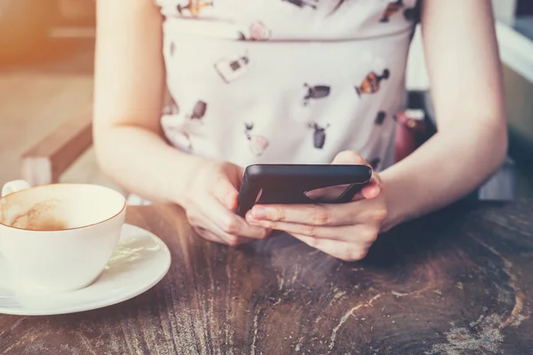 Закрыть руку женщины, пользующейся телефоном в кофейне с глубиной — стоковое фото