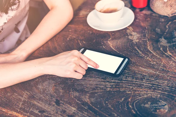Закрыть руку женщины, пользующейся телефоном в кофейне с винтажной футболкой — стоковое фото