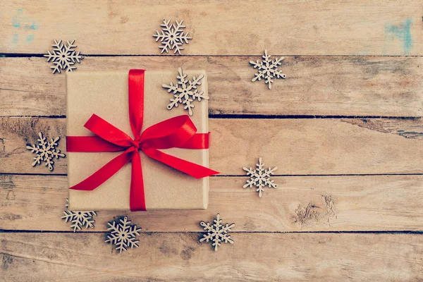Braune Geschenkschachtel und Schneeflocken auf Holz für Weihnachten, Neujahr und Weihnachten — Stockfoto
