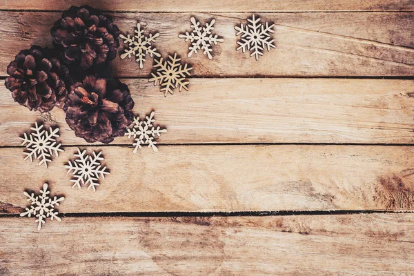 Tannenzapfen und Schneeflocken auf Holz für den weihnachtlichen Hintergrund mit — Stockfoto