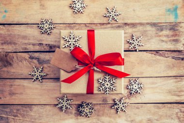 Kahverengi hediye kutusu ve ahşap arka plan üzerinde kar taneleri. Vintage Hediyelik